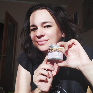 Zufriedene Kundin mit strahlender Haut hält die Hyaluron Tagescreme •Anti Age• mit Lotusextrakt von Pure Elements in der Hand. Sie lächelt und schreibt gerade eine begeisterte Bewertung über ihre Erfahrung. Ihre positive Ausstrahlung unterstreicht die Wirkung der Creme – sichtbare Glättung, Feuchtigkeit und ein gesundes Hautbild dank Lotusextrakt, Bergkristallen und 3-fach Hyaluronsäure.