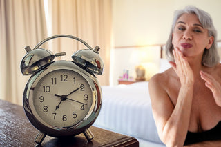 Alte Dame, die sich mit Anti-Age Produkte pflegt, in Vordergrund ist Uhr als Alterungszeichen, im Hintergrund sind die Produkte auf dem Nachttisch. Ihr Schlafzimmer ist hell und angenehm, sie fühlt sich wohl und junger.