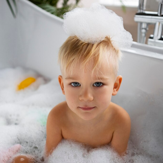 Ein Kind sitzt in der Badewanne mit Wasser und Schaum auf dem Kopf – es verwendet das Baby-Rein 2 in 1 Produkt von Pure Elements. Milde, vegane Naturkosmetik, glutenfrei, BDIH-zertifiziert, tierversuchsfrei und hergestellt in Deutschland