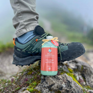 Das Fuß- und Beingel •Energie• mit Rosskastanie von Pure Elements steht im Vordergrund, im Hintergrund ist ein müder Fuß in einem Wanderschuh nach einer Bergtour zu sehen. Ideal zur Erfrischung und Revitalisierung müder Beine. BDIH-zertifiziert, vegan, glutenfrei, tierversuchsfrei, mit echten Bergkristallen.