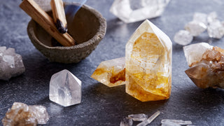 Mehrere klare Bergkristalle auf Platte, daneben Holzstück mit aufsteigendem Rauch – pure, energetische Stimmung